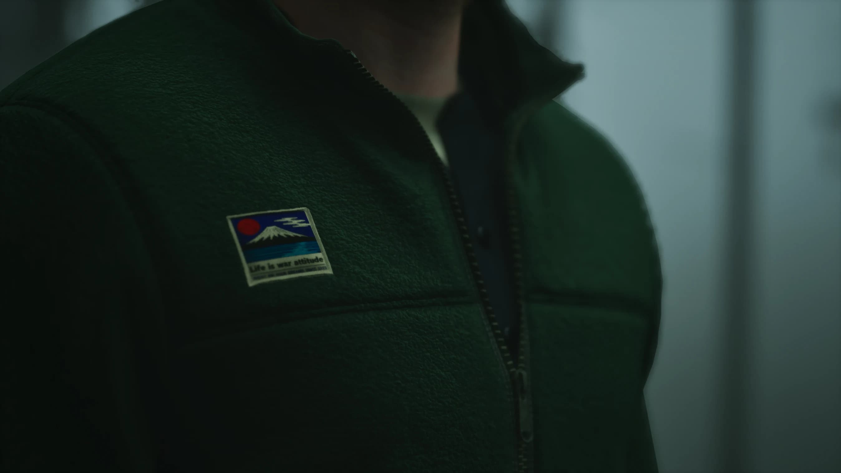 Detalhe aproximado do tecido, costuras, zíper e patch da roupa de Shawn